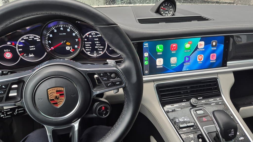 Apple CarPlay na displeji v interiéru Porsche s volantem vlevo